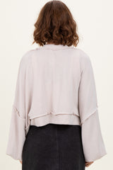 woman wearing a light pink cropped ribbed sweater with bell sleeves, viewed from the back