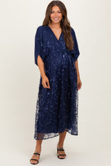woman wearing a navy blue maternity dress with floral embroidery and a flowing skirt, showcasing her baby bump