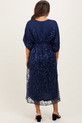 woman wearing a navy blue maternity dress with floral embroidery and a flowy overlay, showing a beautiful back design