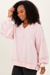 woman wearing a light pink oversized ribbed pullover with a v-neck and balloon sleeves