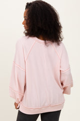 woman wearing a light pink oversized ribbed sweater with three-quarter sleeves and a relaxed fit.