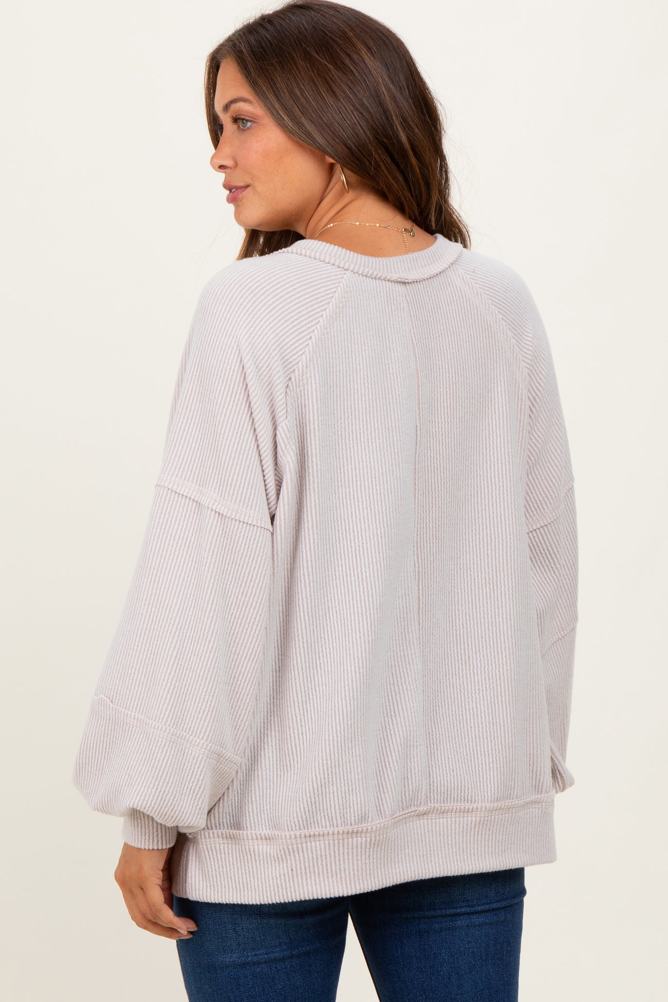 woman wearing a soft pink oversized maternity sweater with balloon sleeves and a relaxed fit, view from the back