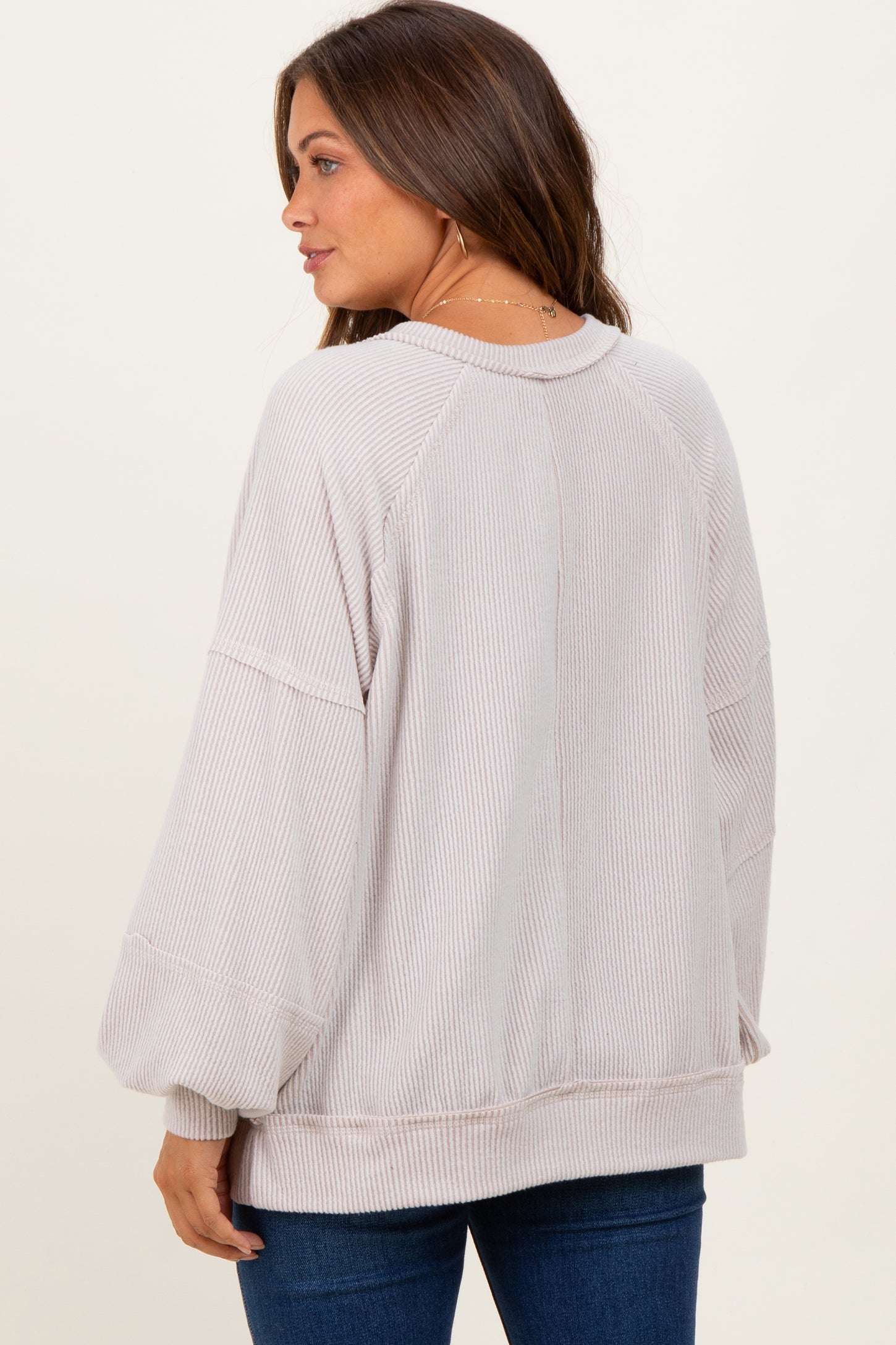woman wearing a soft pink oversized maternity sweater with balloon sleeves and a relaxed fit, view from the back