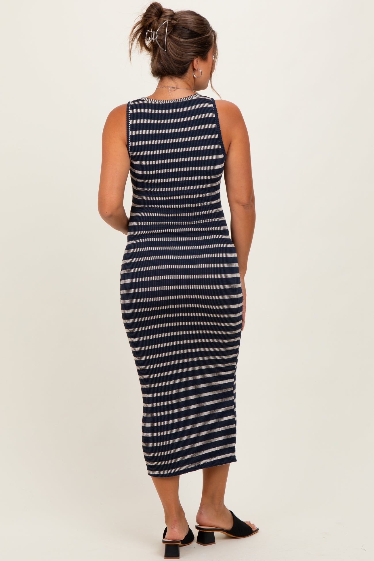 woman wearing a navy and white striped maternity dress with a fitted style and midi length, showing her back