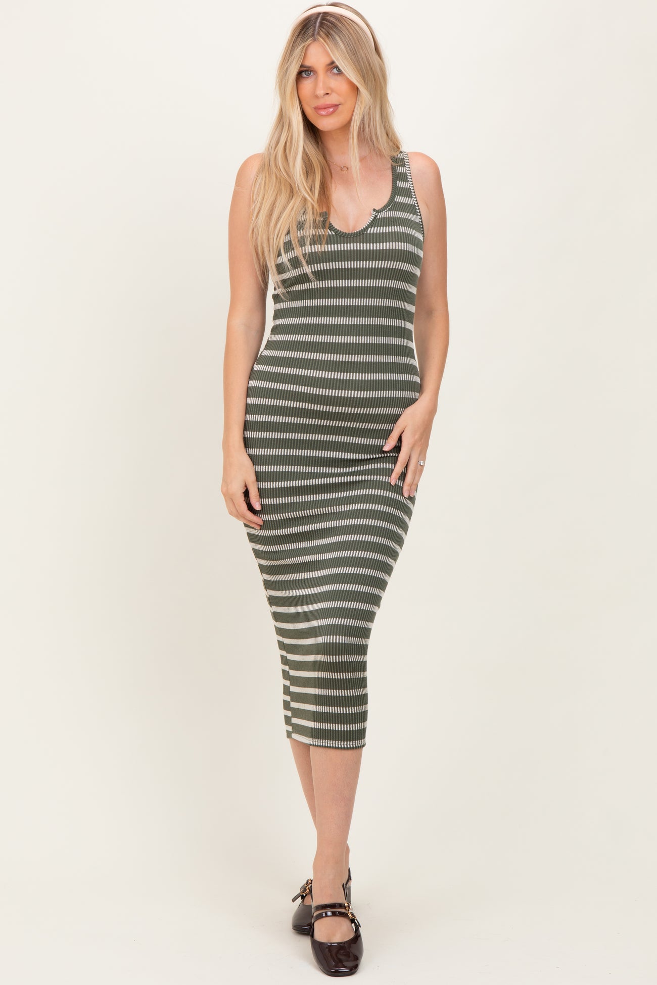 woman wearing a fitted olive green and cream striped midi dress with a scoop neckline and side slit