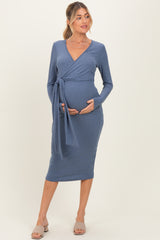 woman wearing a blue maternity wrap dress and holding her baby bump