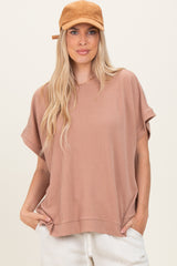 woman wearing a dusty rose oversized ribbed short sleeve top and a tan baseball cap, hands in pockets