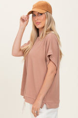 woman wearing a light brown ribbed short sleeve top and a tan baseball cap
