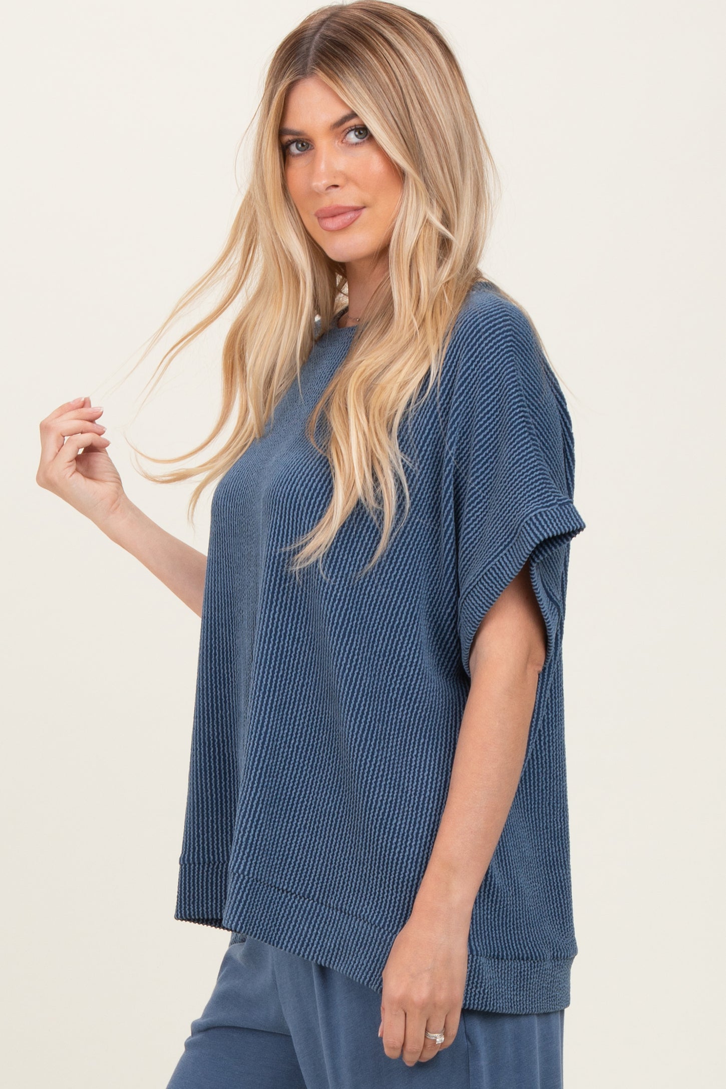 woman wearing a loose-fitting navy blue textured top with short sleeves and a casual style