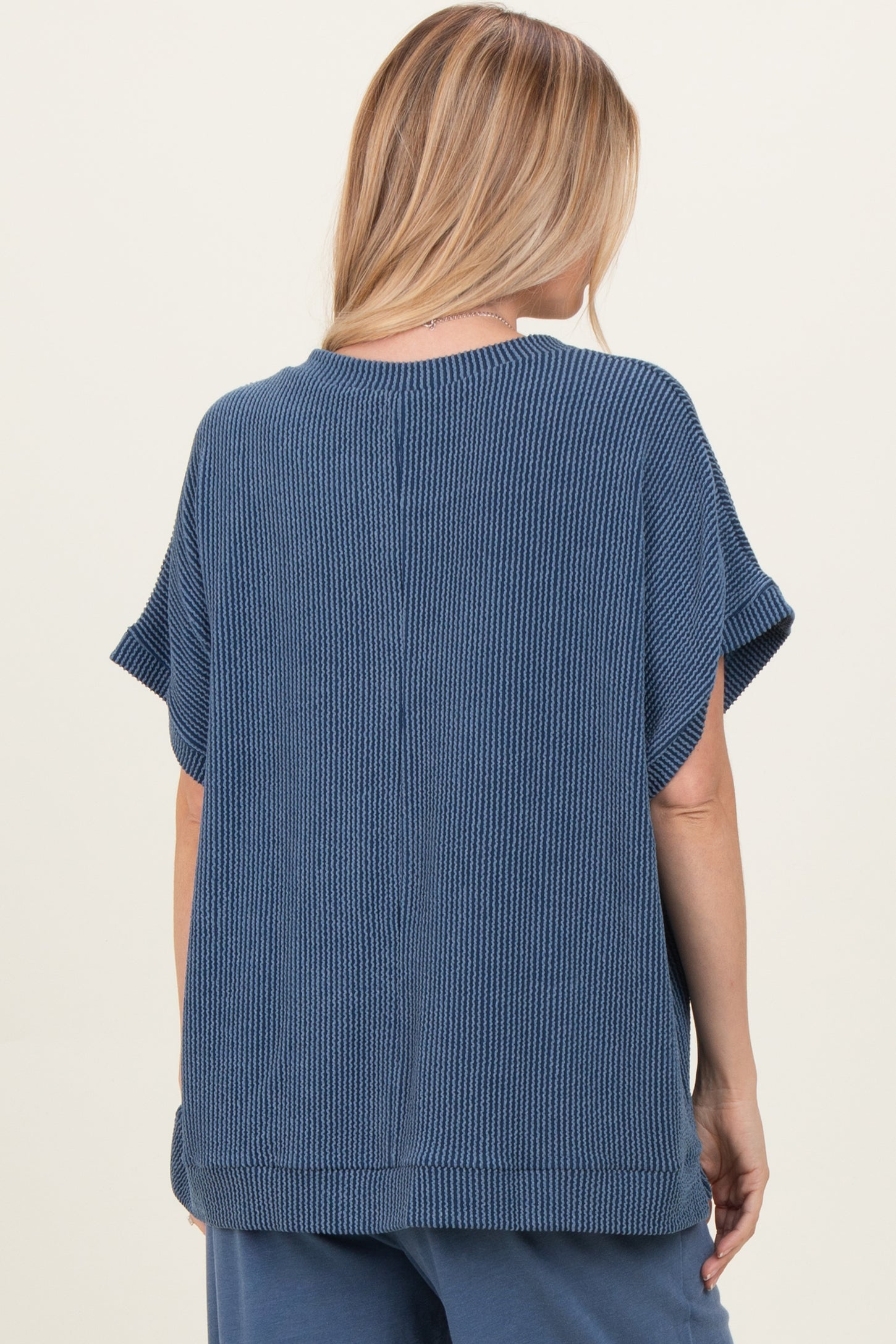 woman wearing a blue striped short sleeve top, view from the back showing loose fit and textured fabric