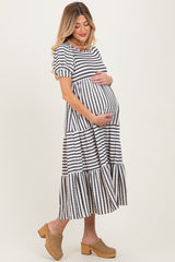 woman wearing a black and white striped maternity dress with short sleeves and a tiered skirt, holding her baby bump