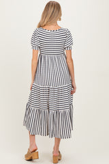 woman wearing a striped navy and white maternity dress with puff sleeves and tiered skirt, seen from the back