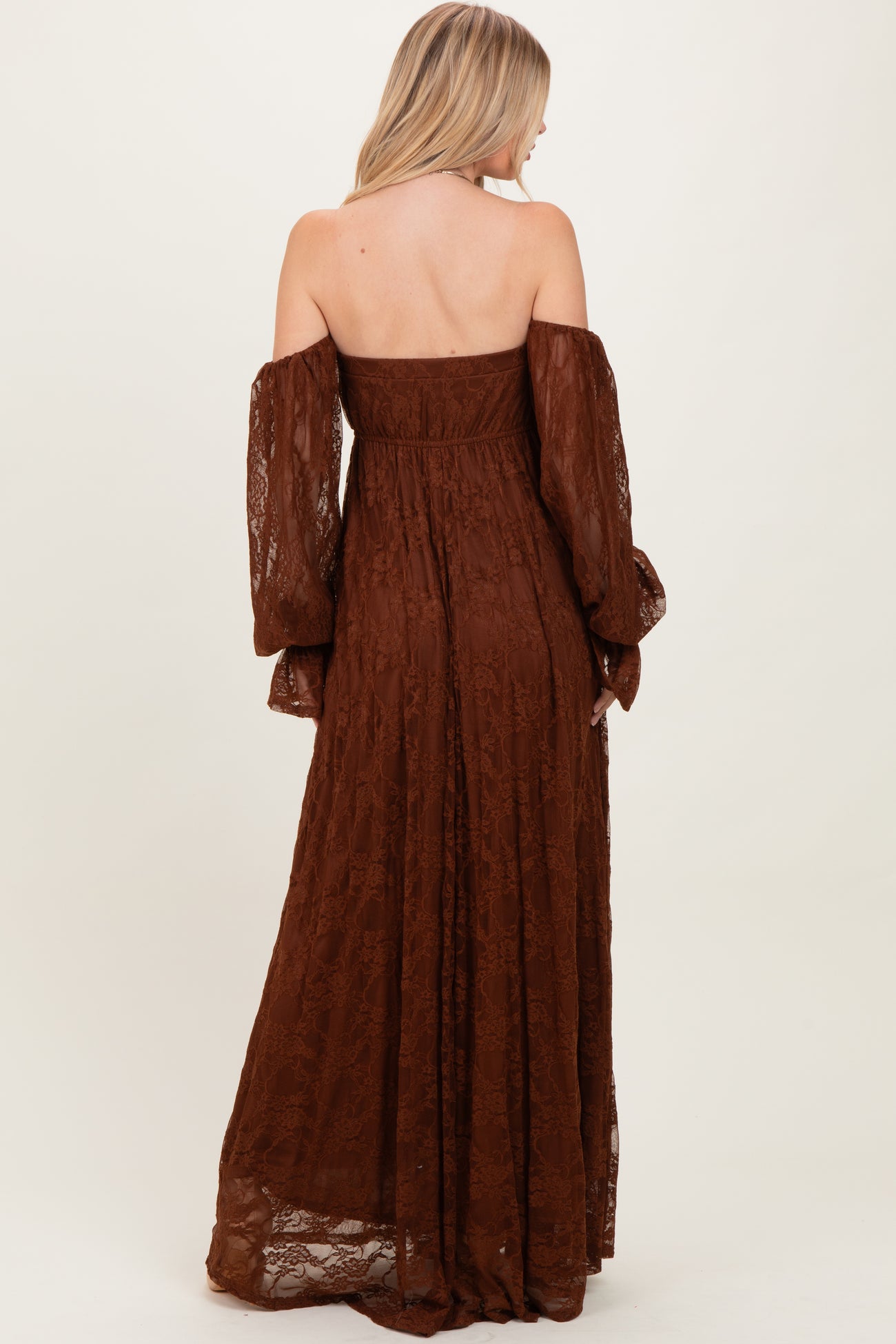 woman wearing a brown off-the-shoulder lace maxi dress with long puff sleeves and a fitted bodice
