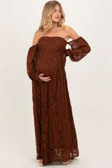 woman wearing a brown off-shoulder lace maternity gown with bell sleeves and holding her baby bump