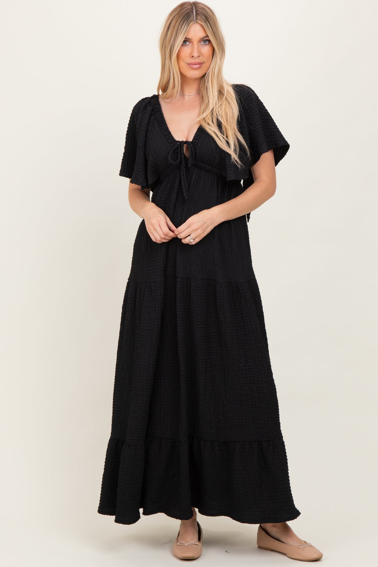 woman wearing a black tiered maxi dress with short sleeves and a tie front detail