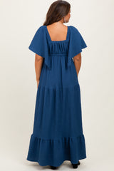 woman wearing a navy blue flutter sleeve maternity maxi dress with a tiered skirt and square back detail