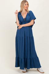 woman wearing a navy blue maxi dress with short flutter sleeves and a tie front detail