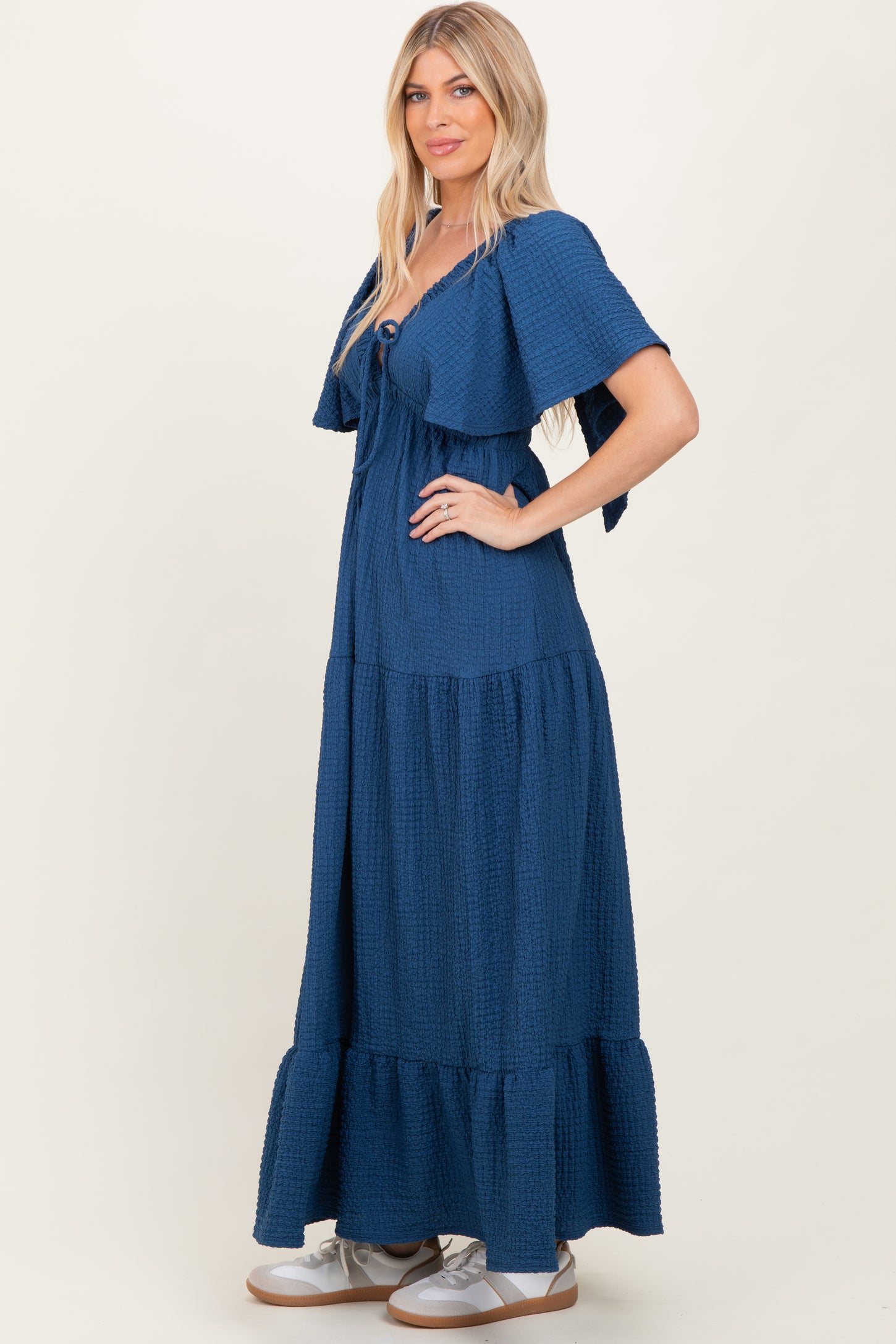 woman wearing a navy blue tiered maxi dress with short sleeves and a button detail on the bodice