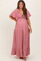 woman wearing a pink tiered maxi maternity dress with flutter sleeves and a baby bump visible