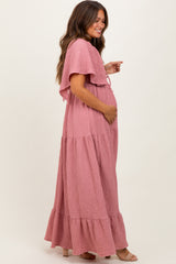 woman wearing a pink maternity maxi dress with flutter sleeves and pockets, showing her baby bump