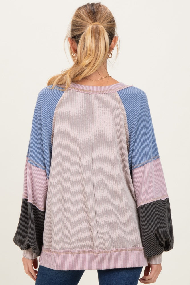 woman wearing a multicolored long sleeve maternity top with balloon sleeves and a relaxed fit, showing back view