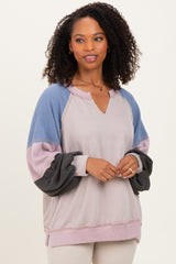 woman wearing a pastel color block long sleeve top with a v-neck and raglan sleeves