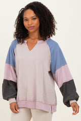 woman wearing a color block long sleeve top with shades of blue, pink, and black