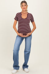 woman wearing a burgundy and white striped maternity top and jeans, holding her baby bump