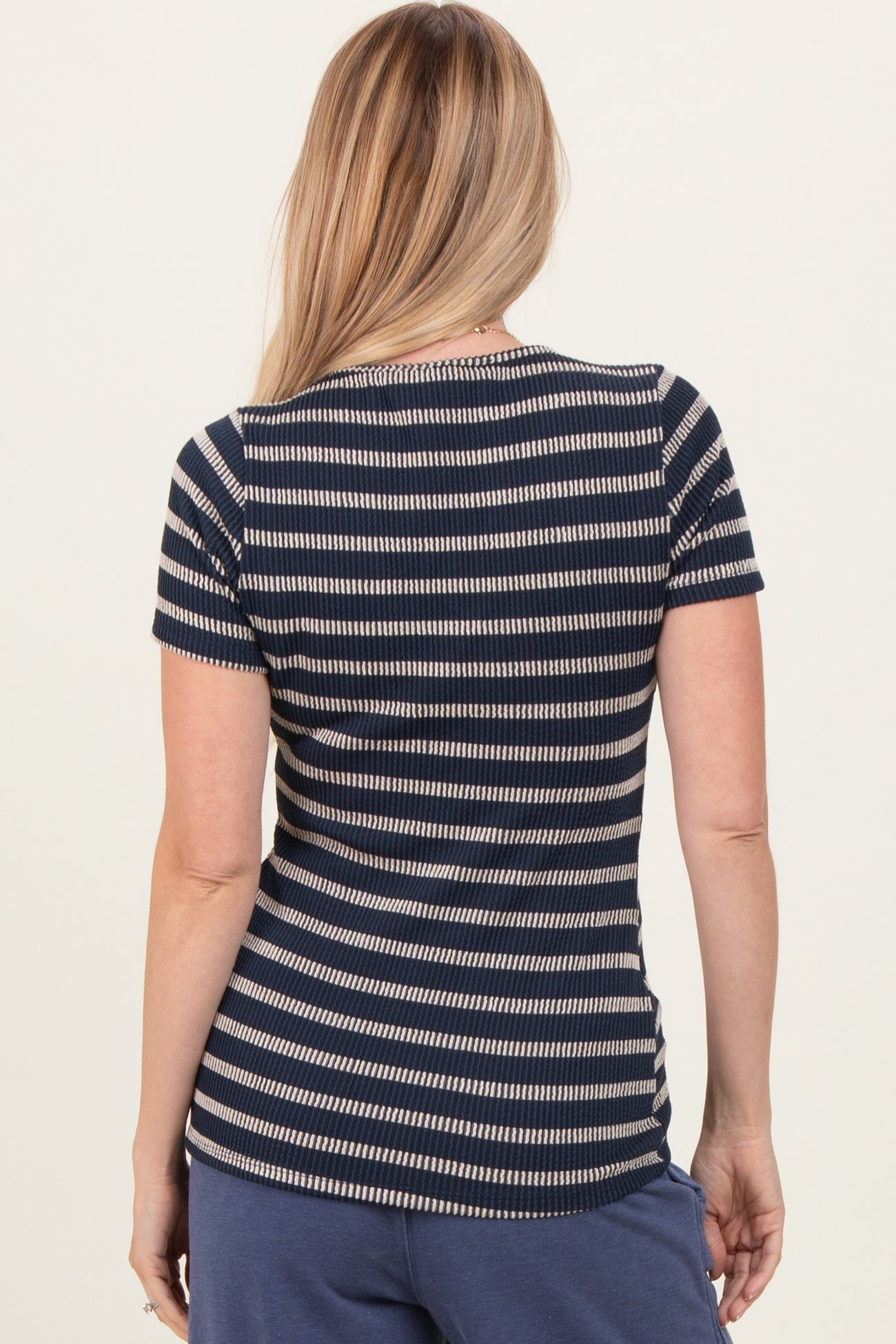 woman wearing a navy and white striped short sleeve top, viewed from the back
