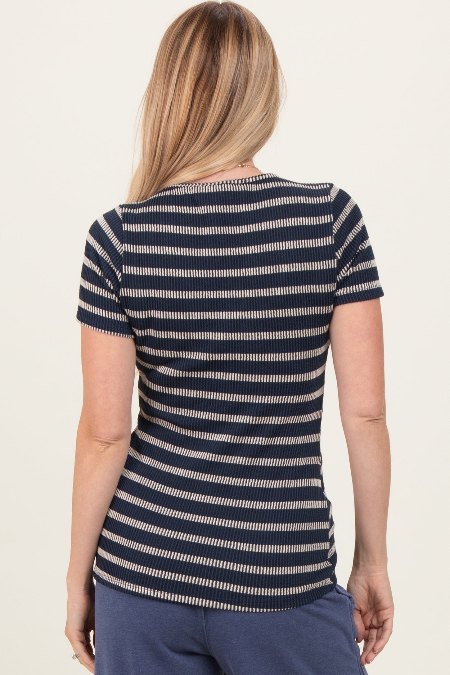 woman wearing a navy and white striped short sleeve top, viewed from the back