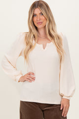 woman wearing a cream ribbed long sleeve top with a v-neck and puffed sleeves