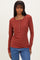 woman wearing a rust long sleeve henley top with button details and light blue jeans