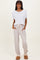 woman wearing a white cropped t-shirt and beige striped drawstring pants, standing in casual slippers