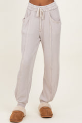 woman wearing light gray ribbed loungewear pants with pockets and drawstring waist, styled with cozy slippers