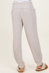 woman wearing light beige ribbed jogger pants with side pockets and a relaxed fit, seen from the back