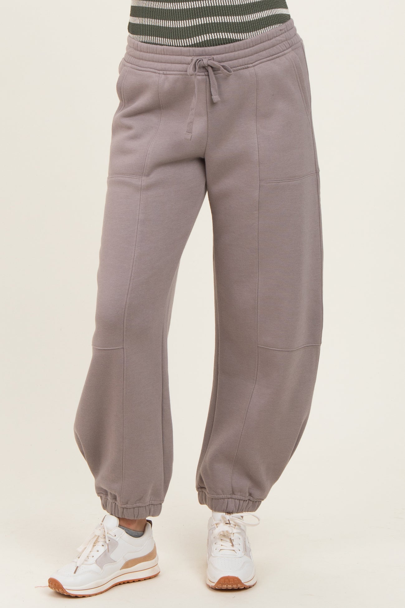 woman wearing gray baggy sweatpants with a drawstring waist and cuffed ankles, paired with white sneakers