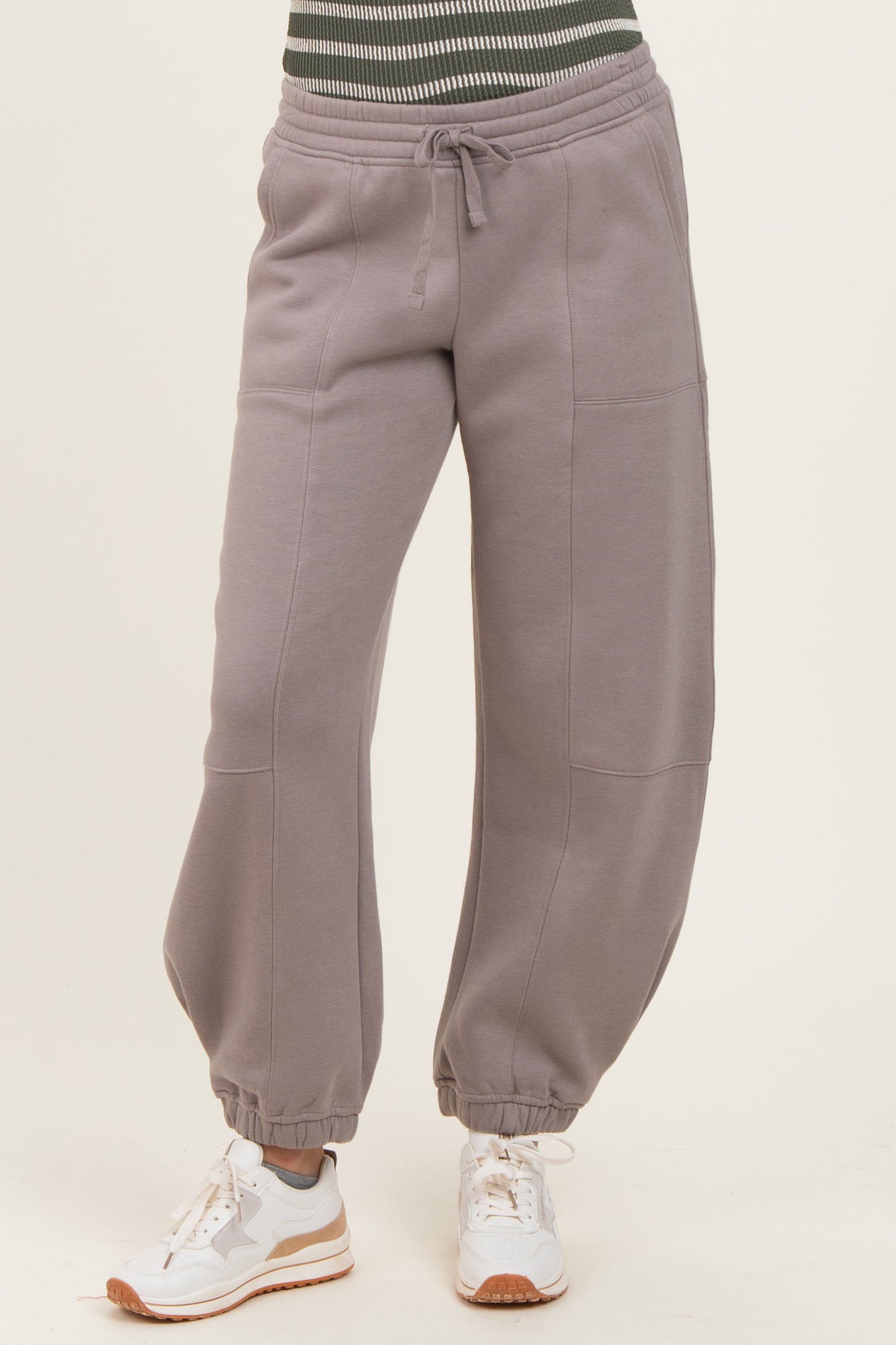 woman wearing gray baggy sweatpants with a drawstring waist and cuffed ankles, paired with white sneakers