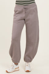 woman wearing gray baggy sweatpants with a drawstring waist and cuffed ankles, paired with white sneakers