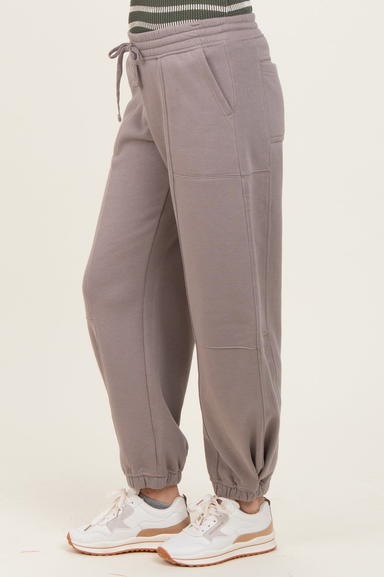 woman wearing gray relaxed fit sweatpants with side pockets and elastic cuffs, paired with white sneakers