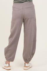 woman wearing gray relaxed-fit jogger pants with elastic cuffs and pockets, standing with her back to the camera