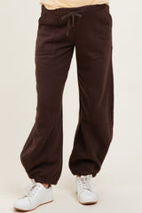 woman wearing brown maternity jogger pants with drawstring and elasticized cuffs, styled with white sneakers