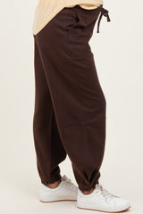 woman wearing brown maternity jogger pants with elastic cuffs and pockets, paired with a light top and white sneakers