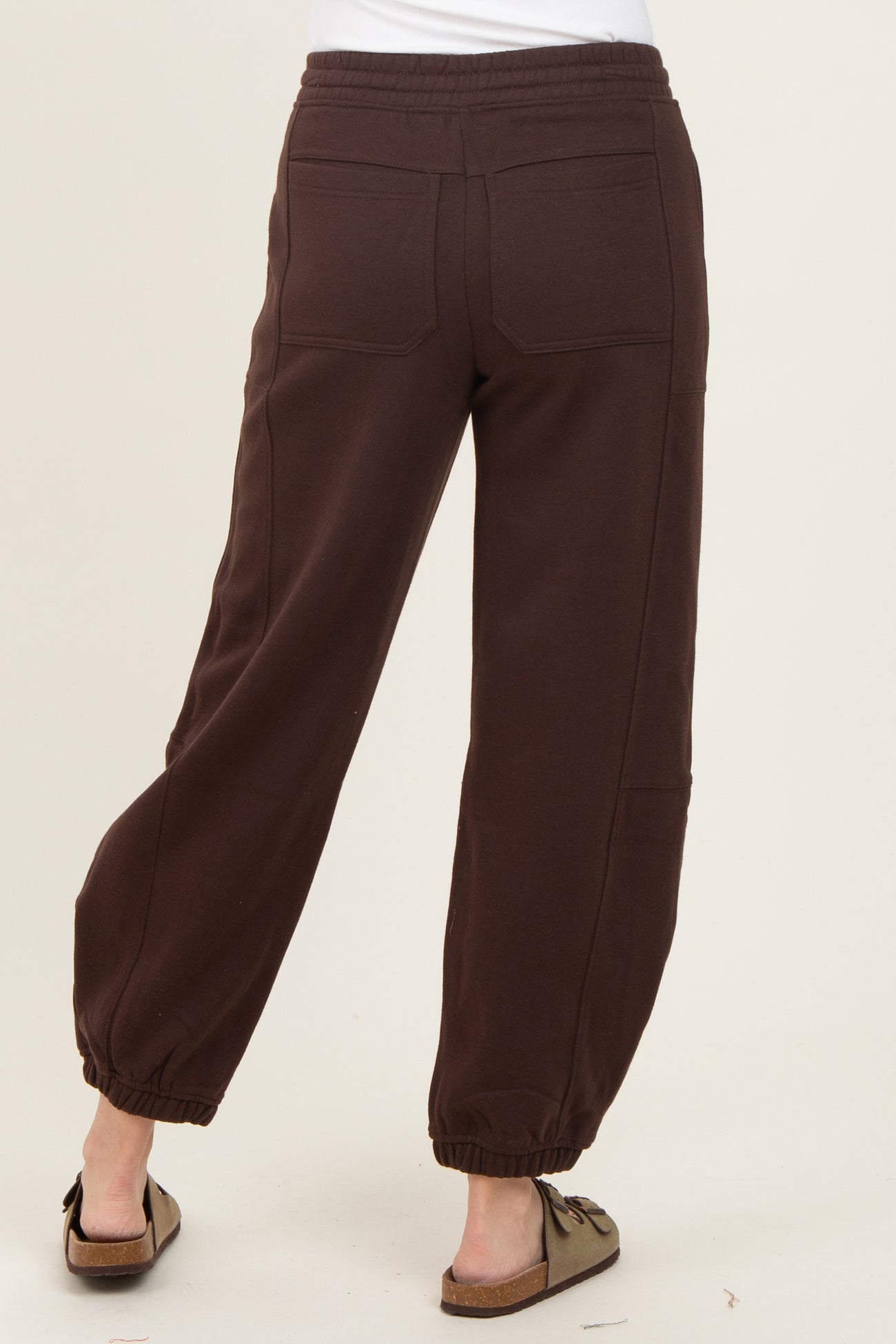 woman wearing brown sweatpants with elastic cuffs and back pockets, viewed from the back