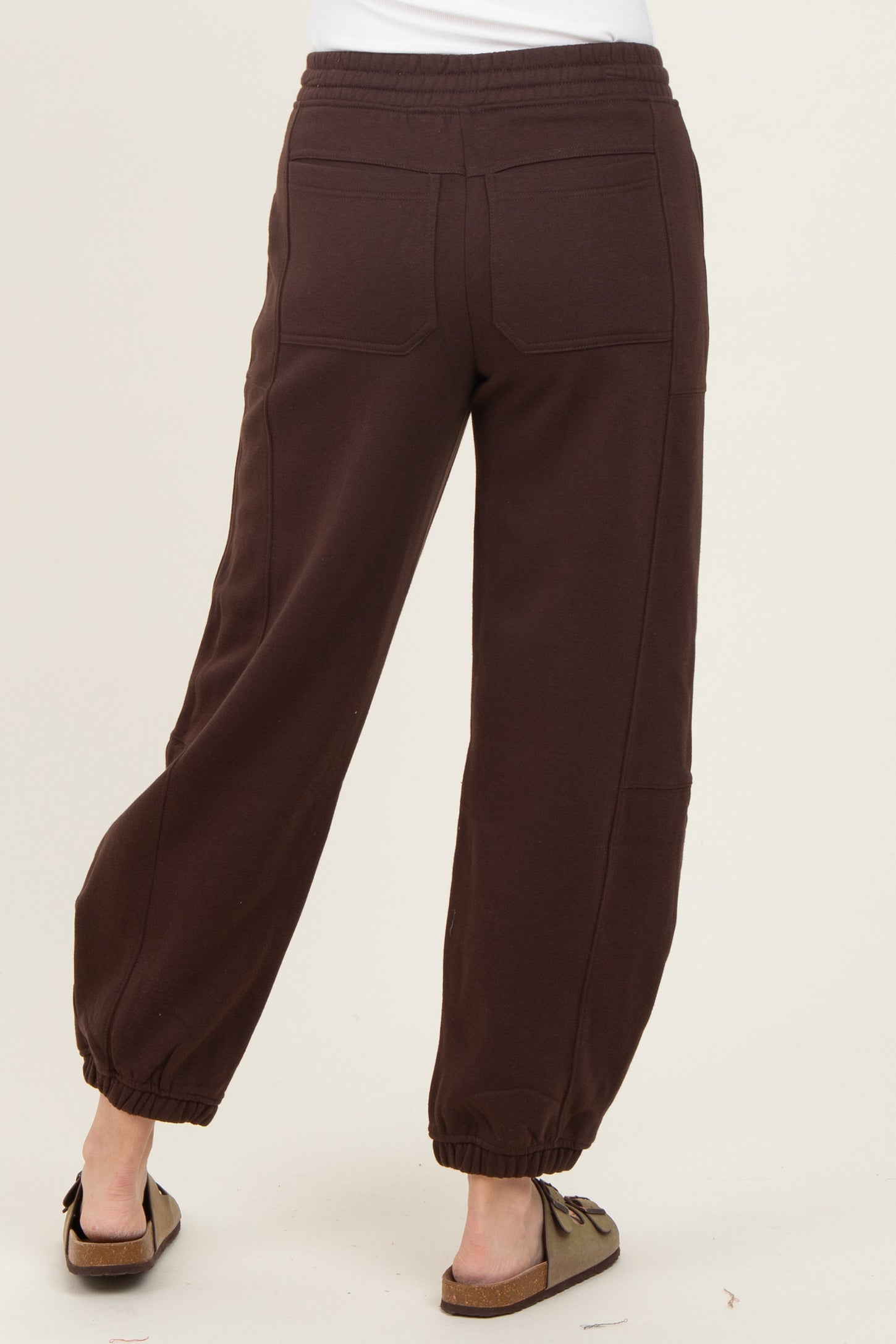 woman wearing brown sweatpants with elastic cuffs and back pockets, viewed from the back