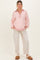 woman wearing a pink and white striped maternity pullover with a collar and beige maternity pants, standing and smiling