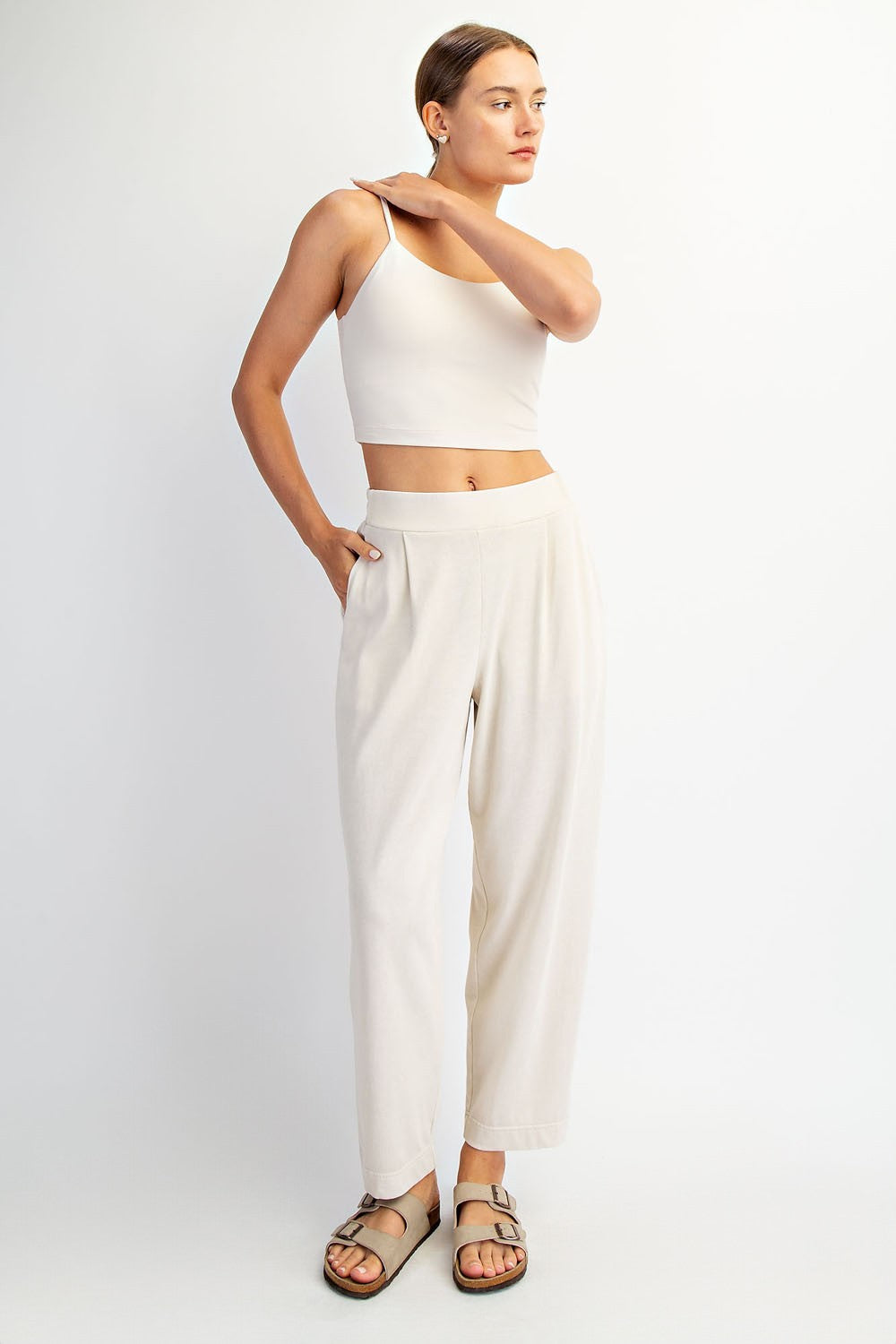 woman wearing a light beige cropped tank top and matching wide-leg pants with pockets