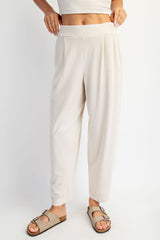 woman wearing cream-colored pleated lounge pants and beige slide sandals