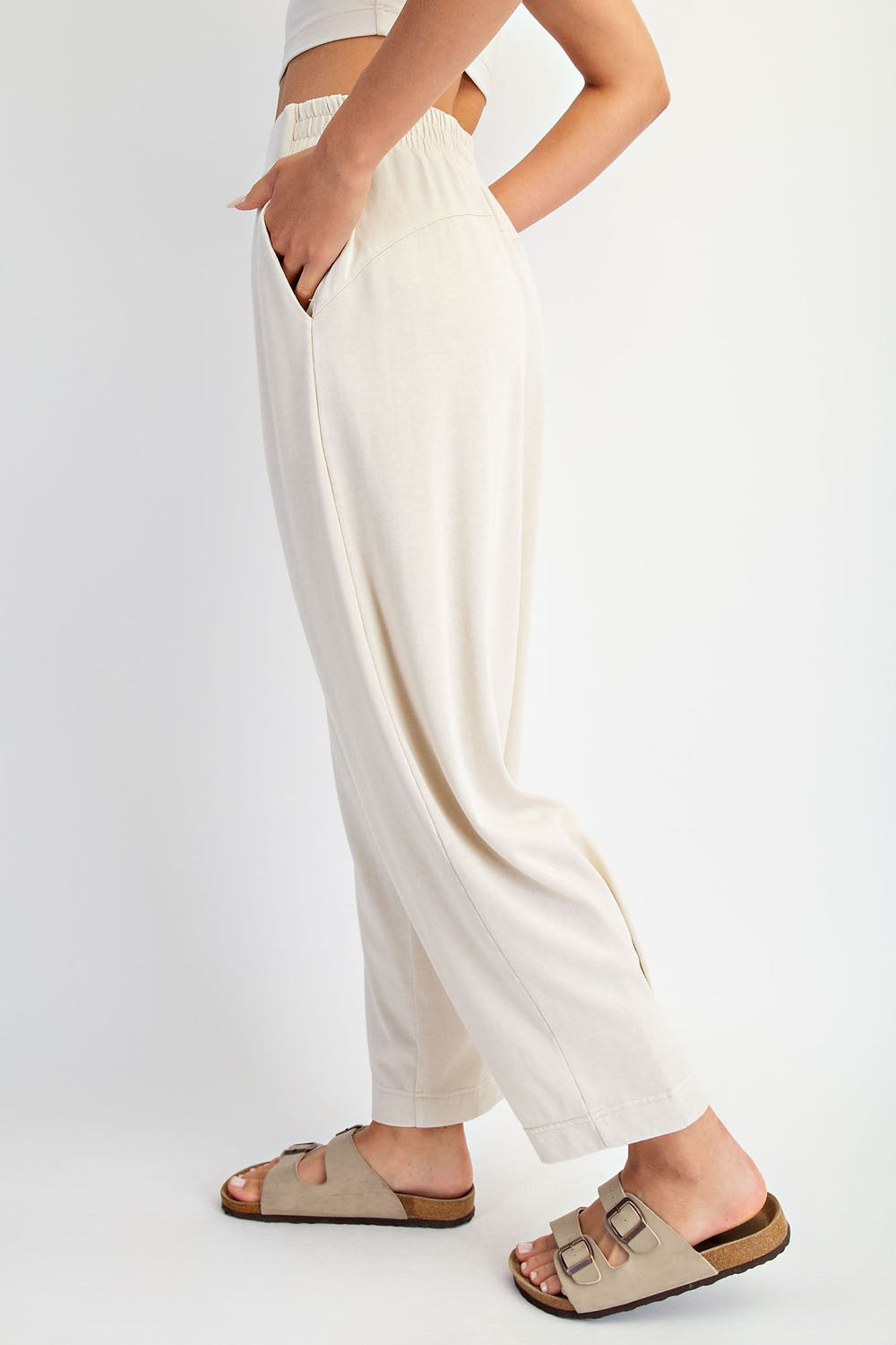 woman wearing beige wide-leg lounge pants with an elastic waistband and side pockets, paired with casual sandals