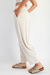 woman wearing beige wide-leg lounge pants with an elastic waistband and side pockets, paired with casual sandals