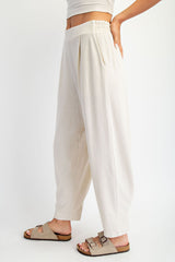 woman wearing light beige high-waisted loose-fit trousers with side pockets and a relaxed silhouette